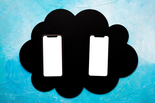 Dos teléfono celular en blanco en negro nube sobre la pared pintada de azul