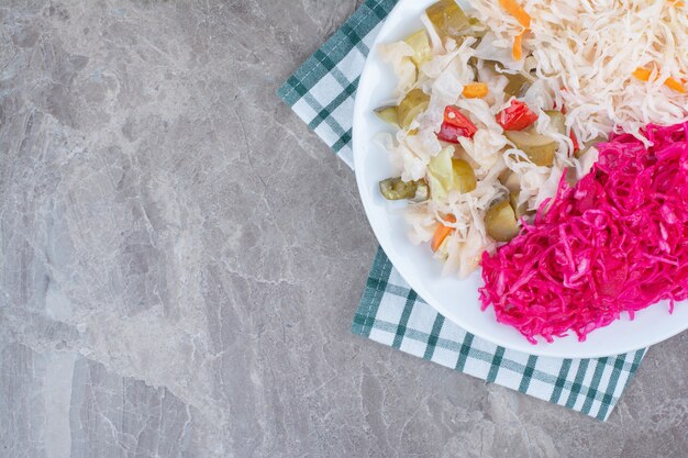 Dos tipos de chucrut y encurtidos en un plato blanco con mantel.