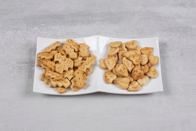 Dos tipos diferentes de galletas saladas en un plato blanco.