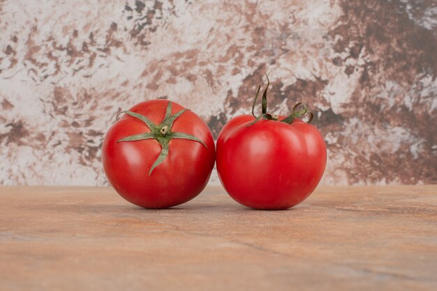 Dos tomates frescos aislados en la mesa de mármol.