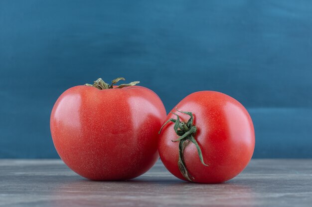 Dos tomates frescos, sobre la mesa de mármol.