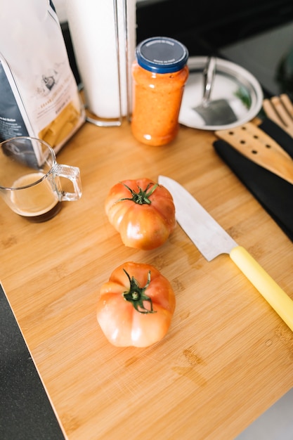 Foto gratuita dos tomates rojos en tajadera con un cuchillo filoso