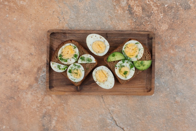 Foto gratuita dos tostadas con pepino y huevos duros en la mesa de mármol.