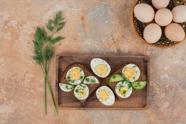 Dos tostadas con pepino y huevos duros en la superficie de mármol