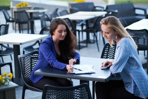 Dos trabajadores cooperativos están discutiendo un nuevo proyecto fuera de la oficina, en la cafetería en un agradable día de verano.