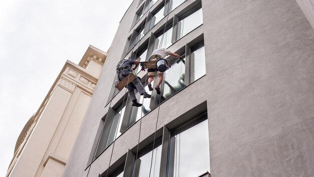 Dos trabajadores lavando ventanas fuera de un edificio