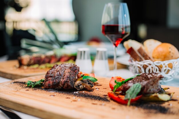 Dos trozos de bistec cocido medio servido con champiñones tomate y calabacín