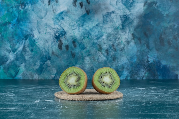 Foto gratuita dos trozos de kiwi sobre salvamanteles, sobre la mesa de mármol.