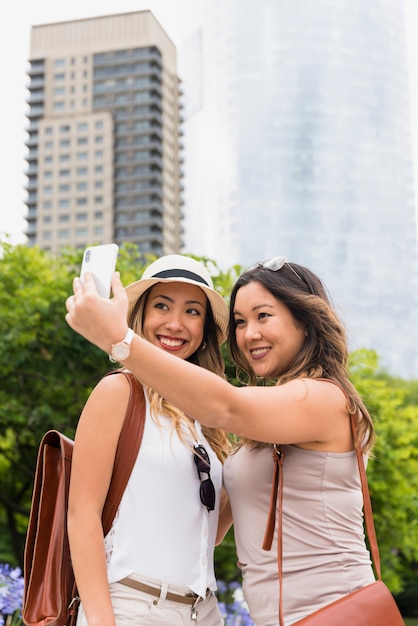 Foto gratuita dos turistas con su mochila tomando selfie en el teléfono celular al aire libre