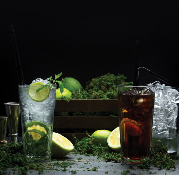 Dos vasos de cócteles fríos de verano con jarabes de frutas y cubitos de hielo.