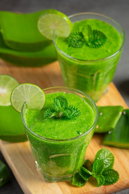 Dos vasos de jugo de aloe vera en tabla de cortar de madera