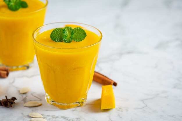 Dos vasos de jugo de calabaza colocan sobre un piso de mármol blanco