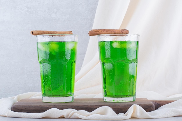 Dos vasos de jugo de estragón con hielo sobre tabla de madera. Foto de alta calidad