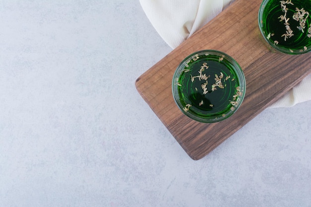 Foto gratuita dos vasos de jugo de estragón con hierbas sobre tabla de madera. foto de alta calidad