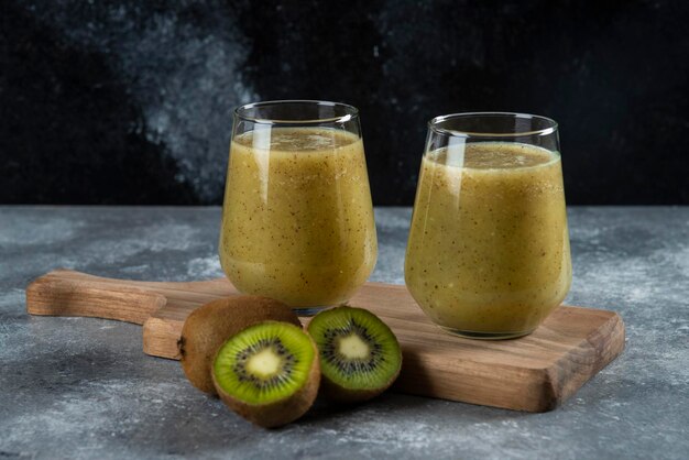 Dos vasos de jugo de kiwi sobre tabla de madera.