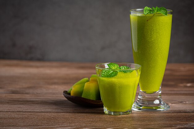 Dos vasos de jugo de melón puestos sobre un piso de madera