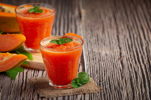 Dos vasos de jugo de papaya puestos sobre un piso de madera