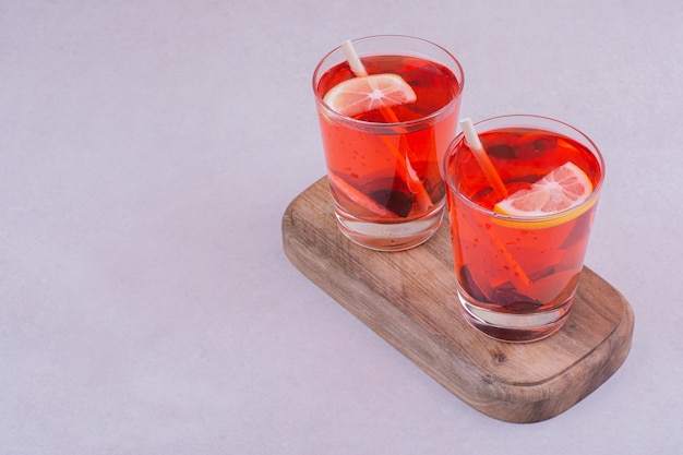 Dos vasos de jugo rojo sobre una tabla de madera