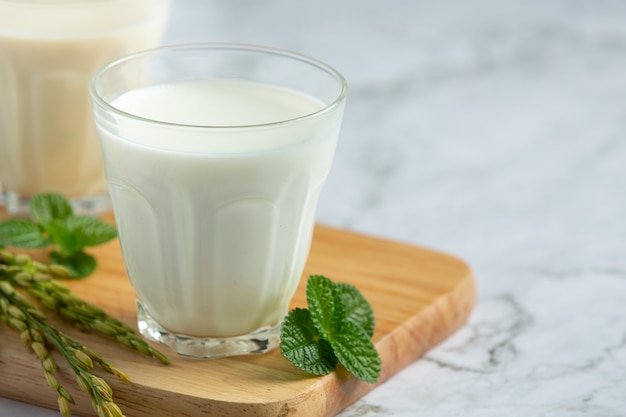 Dos vasos de leche de arroz con planta de arroz en bord de madera