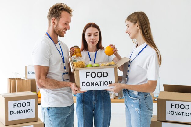 Dos voluntarios sosteniendo la caja de donación de alimentos mientras otro la llena