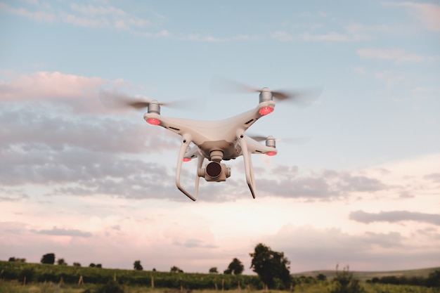 Drone blanco flotando en un cielo azul brillante