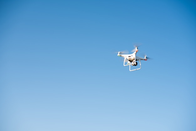 Drone blanco vuela en el cielo grabando un video