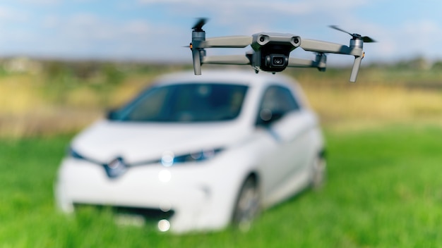 Drone volador disparando un coche eléctrico aparcado en la naturaleza