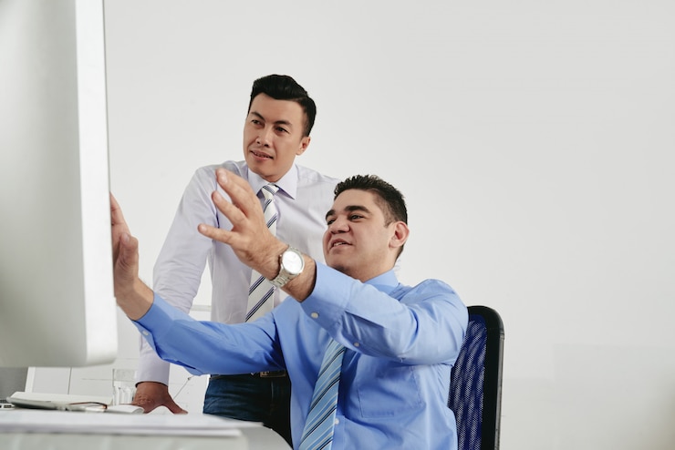 Photo Gratis dua kolega melakukan brainstorming di kantor sambil melihat layar komputer