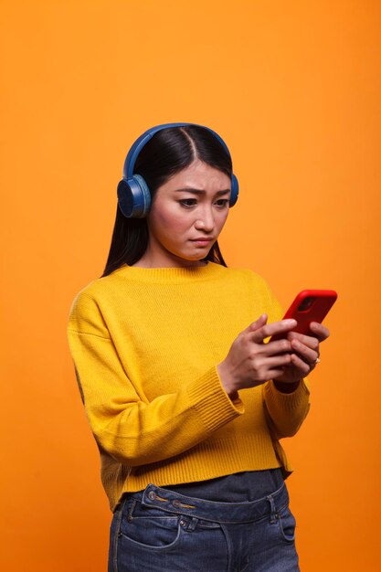 Dudoso adulto joven incierto que se siente confundido debido a que el teléfono inteligente actúa de manera extraña. Mujer confusa y despistada que se siente impotente debido a un dispositivo de teléfono inteligente defectuoso.