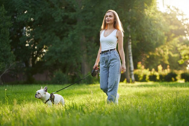 Dueño de perro hembra caminando con bulldog francés en el parque