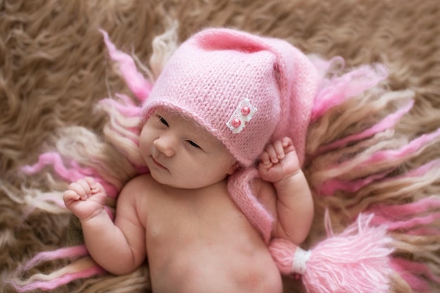 Dulce bebé recién nacido con gorra rosa y ojos abiertos se despierta