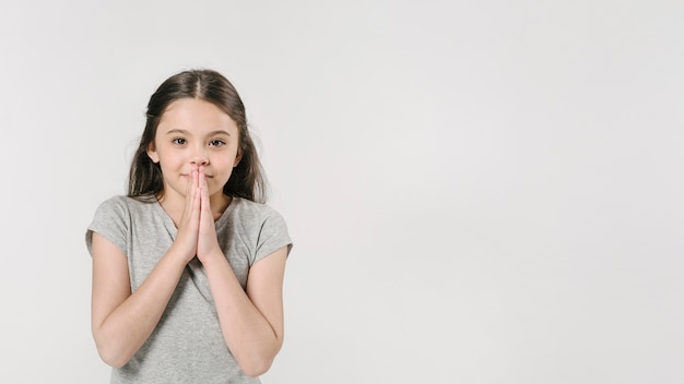 Dulce niña en estudio con las manos juntas