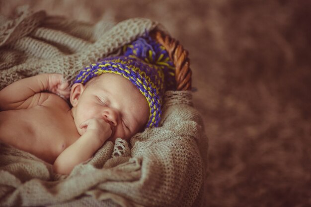 Dulce niño en sombrero de lana duerme en la cesta