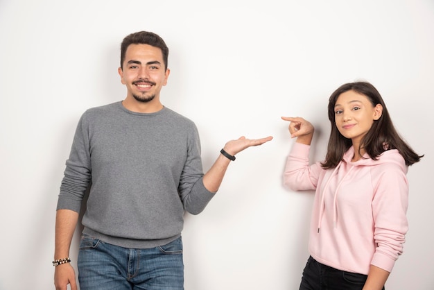 Dulce pareja apuntando a sí mismos en blanco.