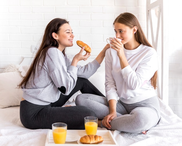 Dulce pareja de lesbianas desayunando en la cama