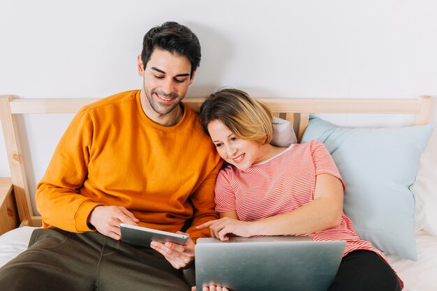 Dulce pareja usando tecnologías en la cama