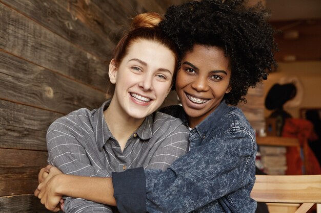 Dulce tierna toma interior de feliz pareja homosexual interracial abrazándose y abrazándose en el café