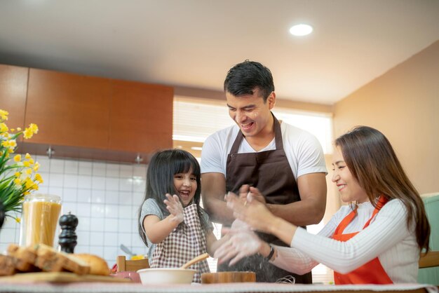 Dulces actividades familiares de fin de semana cocinando junto con el momento de felicidad de papá, mamá e hija y el alegre fondo de la cocina hogareña