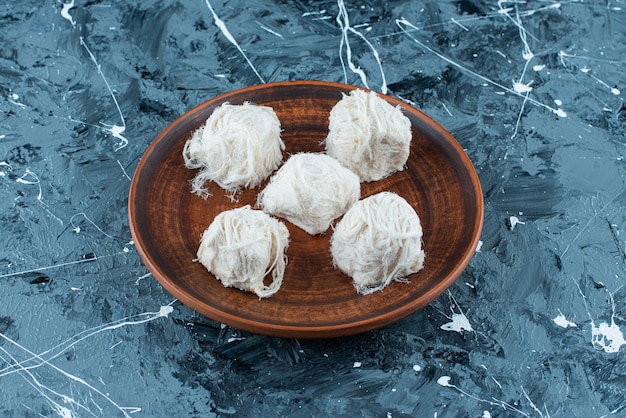 Foto gratuita dulces de algodón turco tradicional en una placa de madera, sobre la mesa azul.