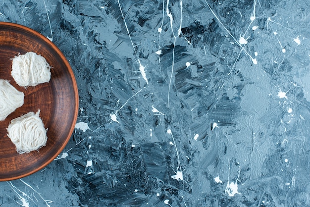 Foto gratuita dulces de algodón turco tradicional en una placa de madera, sobre la mesa azul.