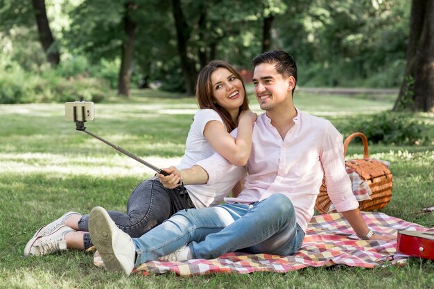 Dulces amantes tomando selfie en picnic