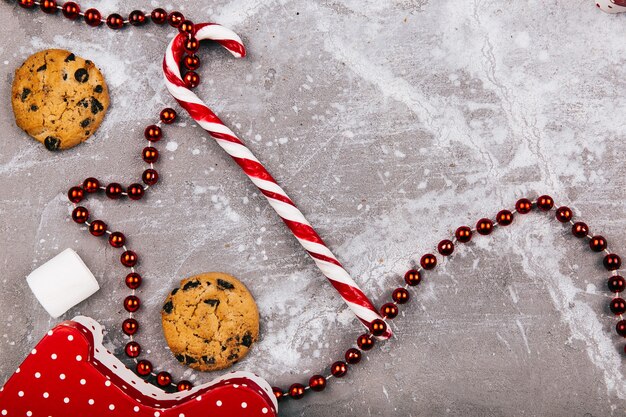 Dulces blancos rojos, galletas, malvavisco se encuentran en piso gris