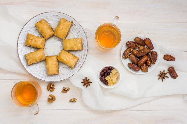 Foto gratuita dulces orientales con dátiles frutales y tazas de té.