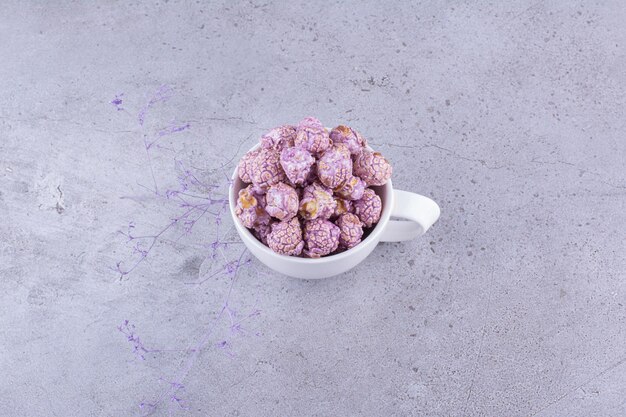 Dulces de palomitas de maíz morados servidos en una taza de té sobre fondo de mármol. Foto de alta calidad