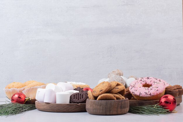 Dulces pasteles navideños con bolas sobre superficie blanca