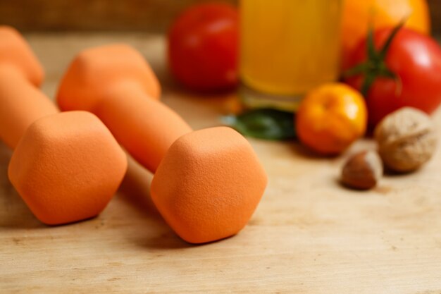 Dumbbell, jugo de naranja, frutas y nueces en la mesa de madera, deporte y concepto de estilo de vida de salud