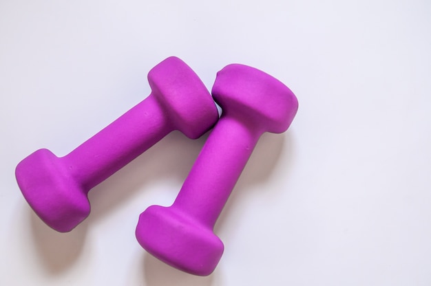 Dumbbells púrpura, concepto de fitness aislado sobre fondo blanco, concepto de fitness aislado sobre fondo blanco, el deporte, el edificio del cuerpo. Concepto estilo de vida saludable, el deporte y la dieta. Equipo de deporte. Copiar espacio