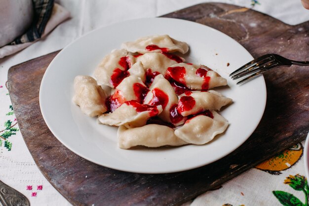 Dushpere famoust comida oriental con masa dentro de carne picada salada con pimienta dentro de un plato blanco con salsa roja