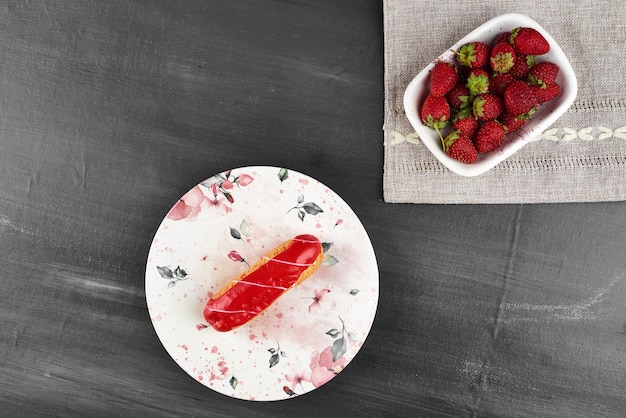 Eclair de fresa con una taza de frutas.