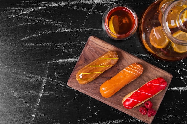 Eclairs en bandeja de madera con bebida.